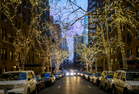 New york city street and brownstone buildings with trees covered in Christmas white lights one point perspective car dusk or early morning stock photo